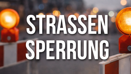 Straßenabsperrung mit rot-weißer Bake und gelben Warnleuchten, darüber der Schriftzug „Straßensperrung“.