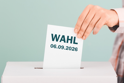 „Symbolbild zur Oberbürgermeisterwahl am 6. September 2026: Eine Hand wirft einen Stimmzettel in eine Wahlurne.“